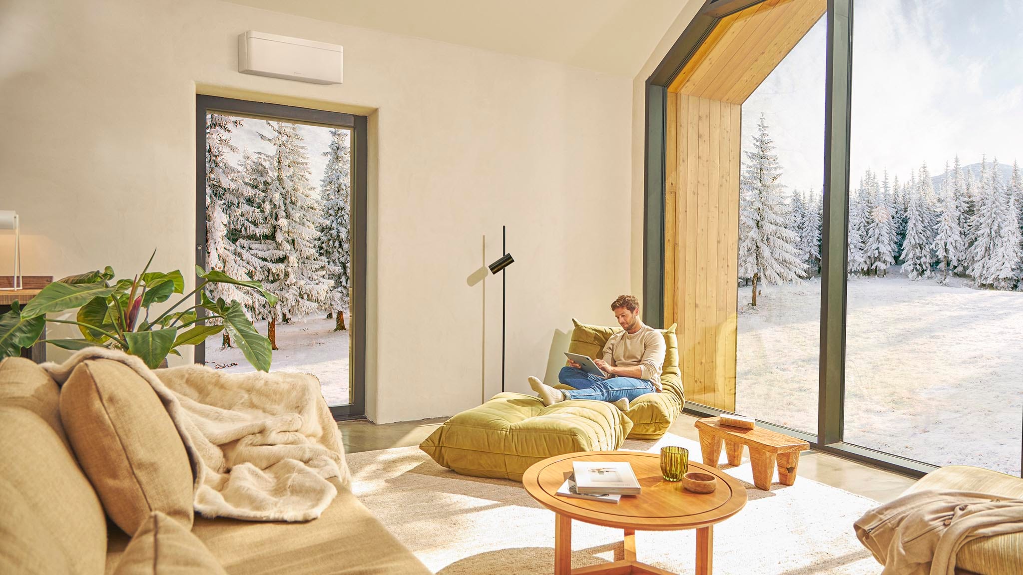 En man sitter i soffan och njuter av behaglig värme från en luftvärmepump