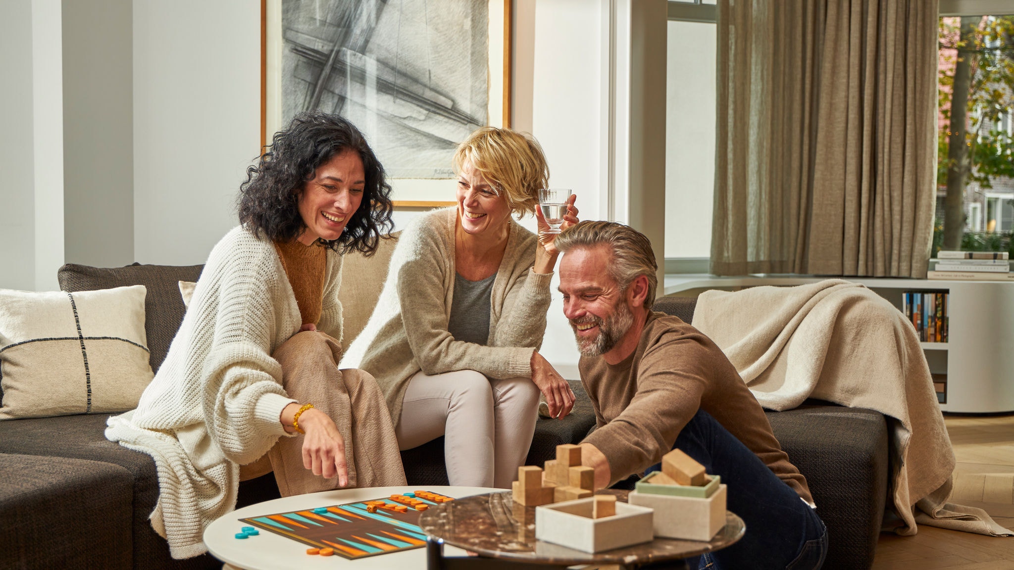 Två kvinnor och en man som spelar ett brädspel