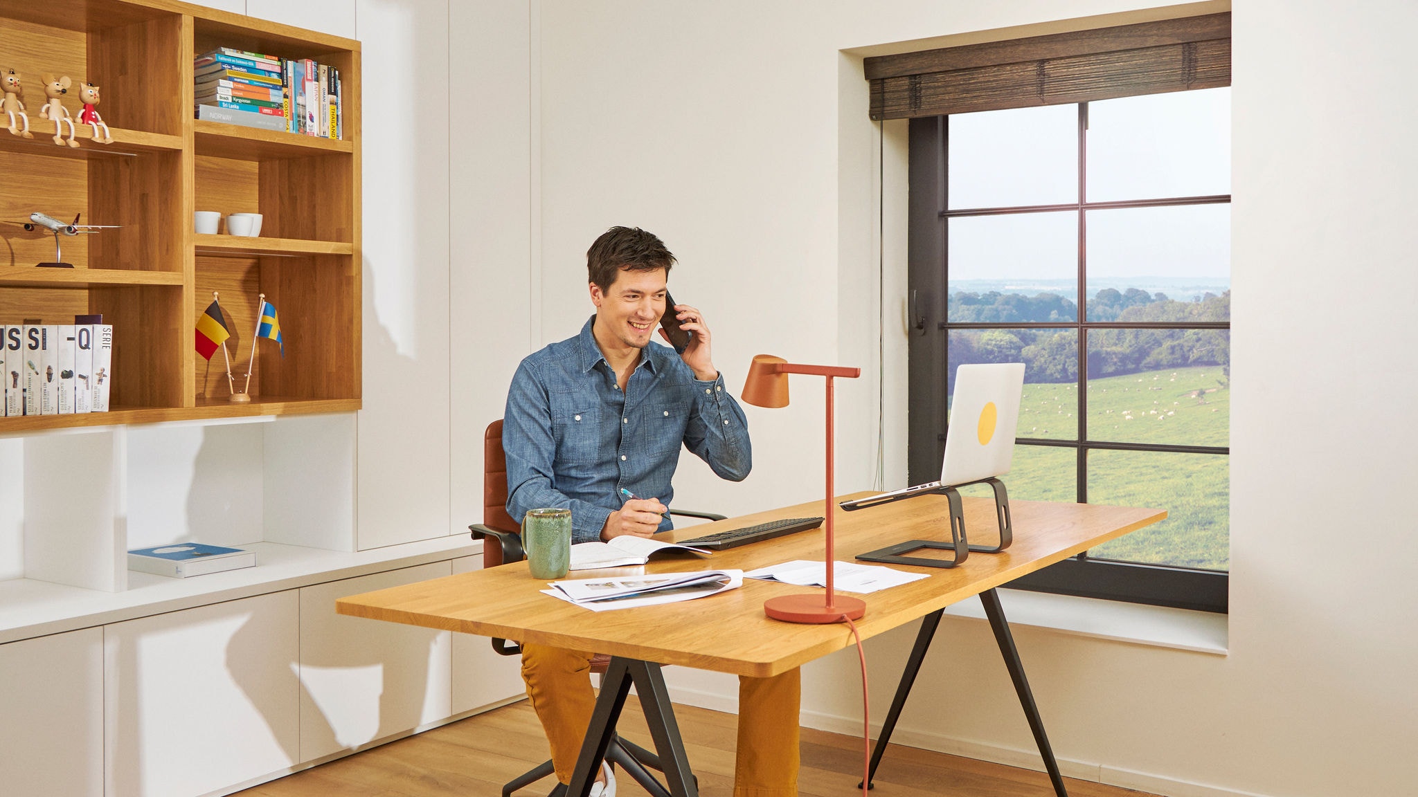 En man vid sitt skrivbord, som ringer någon från sitt hemmakontor i inomhusluft av god kvalitet