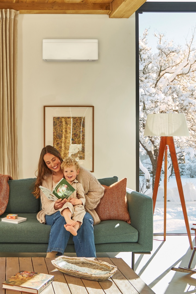 Mor och dotter läser en bok på soffan i behaglig temperatur