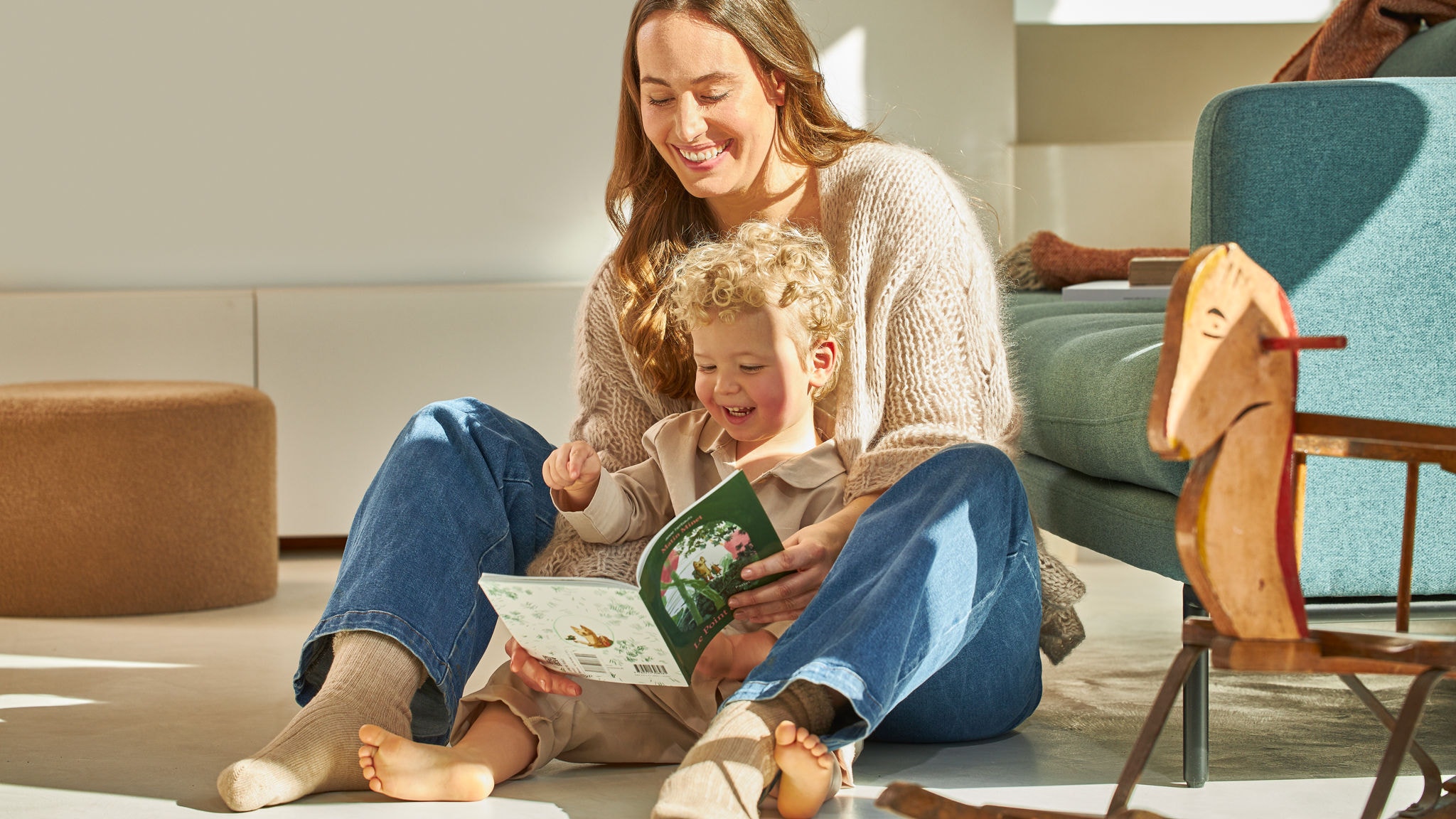 Mamma med sin lilla son som leende sitter och tittar i en bok